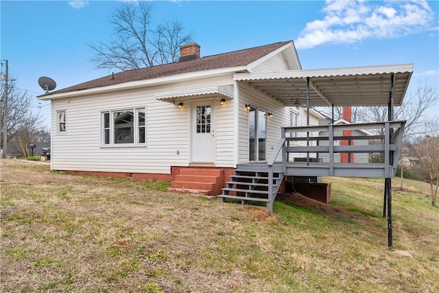 back of property featuring a deck and a lawn