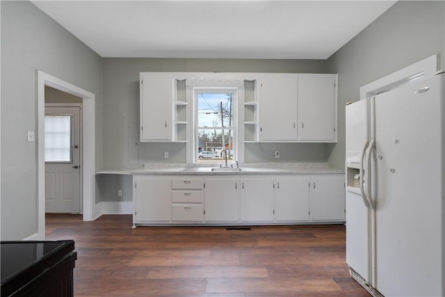 kitchen with sink, dark hardwood / wood-style floors, white fridge with ice dispenser, and white cabinets