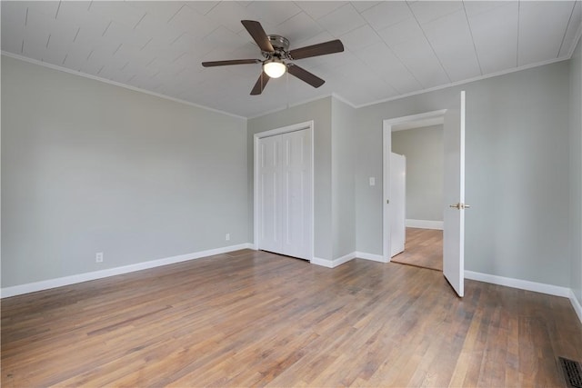 unfurnished bedroom with ceiling fan, ornamental molding, wood-type flooring, and a closet