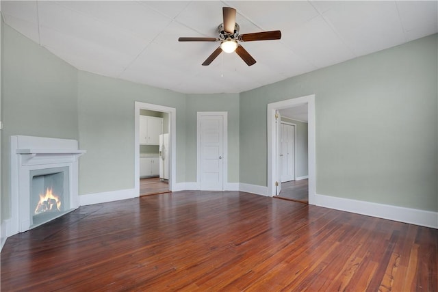 unfurnished living room featuring dark wood-type flooring and ceiling fan