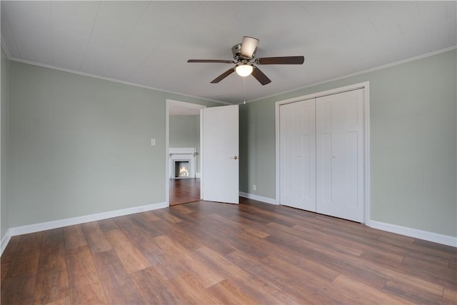 unfurnished bedroom featuring hardwood / wood-style flooring, ceiling fan, crown molding, and a closet