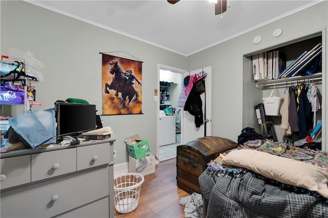 bedroom with ornamental molding, a closet, hardwood / wood-style flooring, ceiling fan, and washer / clothes dryer