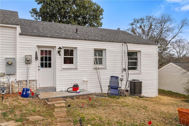 rear view of house featuring central AC and a lawn