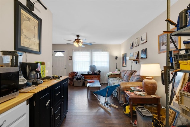 living room featuring ceiling fan and dark hardwood / wood-style flooring