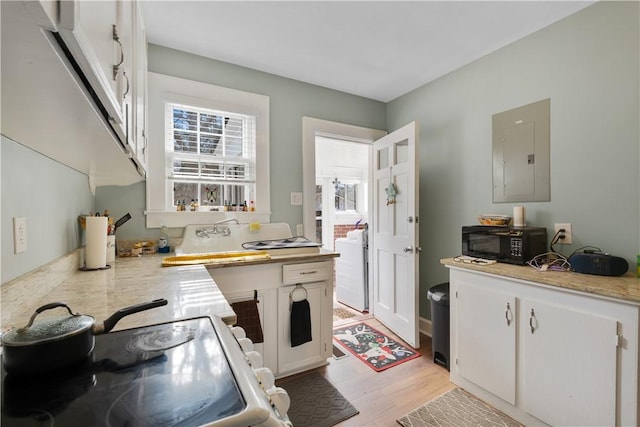 kitchen featuring sink, electric panel, white cabinets, and light wood-type flooring