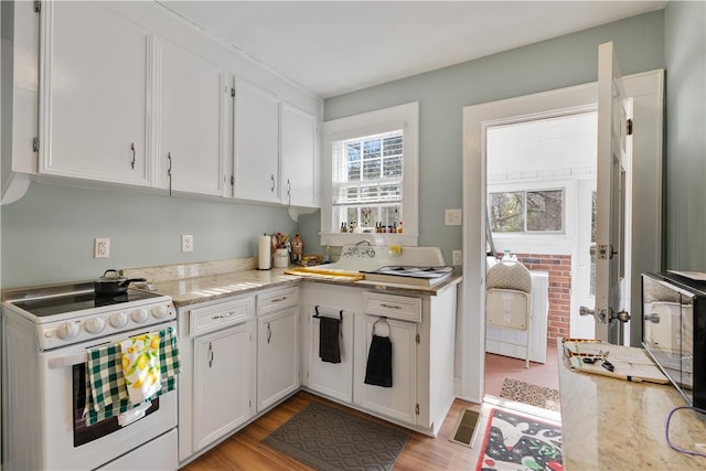 kitchen with white cabinetry, light stone counters, electric range, and light hardwood / wood-style flooring