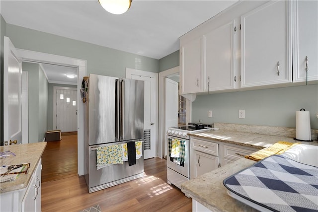 kitchen with hardwood / wood-style flooring, white cabinetry, stainless steel fridge, and white range with electric stovetop