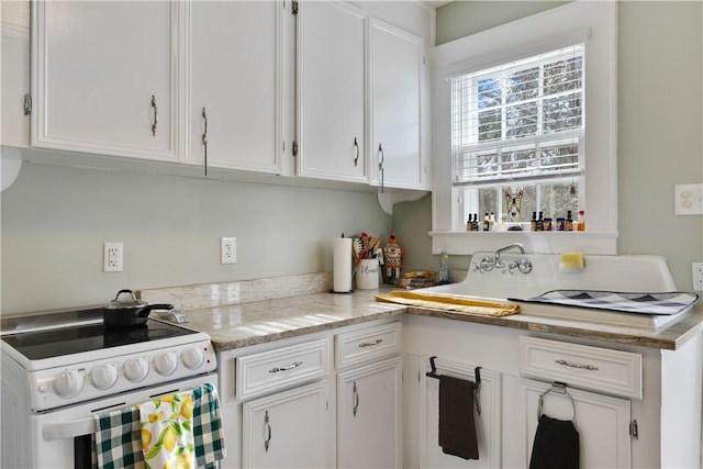 kitchen with white cabinetry, light stone countertops, sink, and white range with electric stovetop