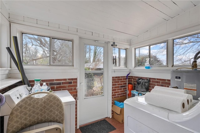 laundry area featuring a wealth of natural light, water heater, and brick wall