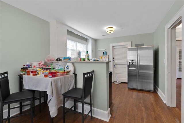 kitchen featuring stainless steel refrigerator with ice dispenser, white cabinetry, a kitchen breakfast bar, dark hardwood / wood-style flooring, and kitchen peninsula