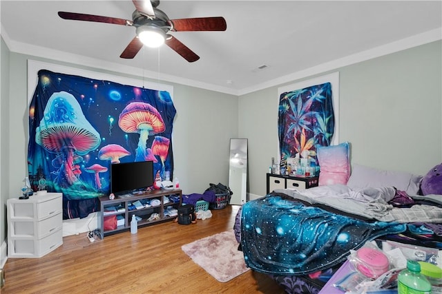 bedroom with crown molding, hardwood / wood-style flooring, and ceiling fan