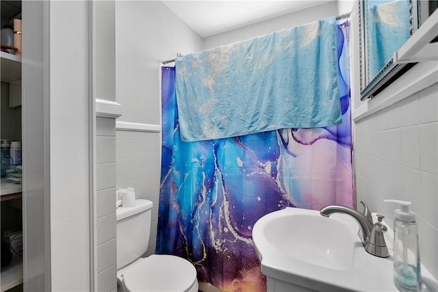 bathroom featuring walk in shower, toilet, sink, and tile walls