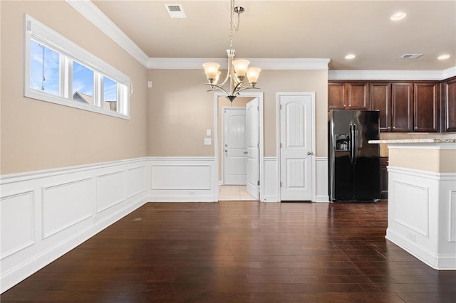 unfurnished dining area featuring crown molding, dark wood-type flooring, and a notable chandelier