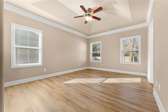 unfurnished room with ceiling fan, crown molding, light wood-type flooring, and a tray ceiling