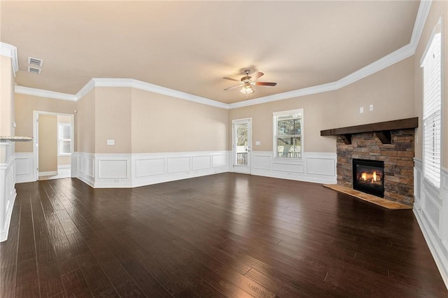 unfurnished living room featuring dark wood-type flooring, ceiling fan, a stone fireplace, and crown molding