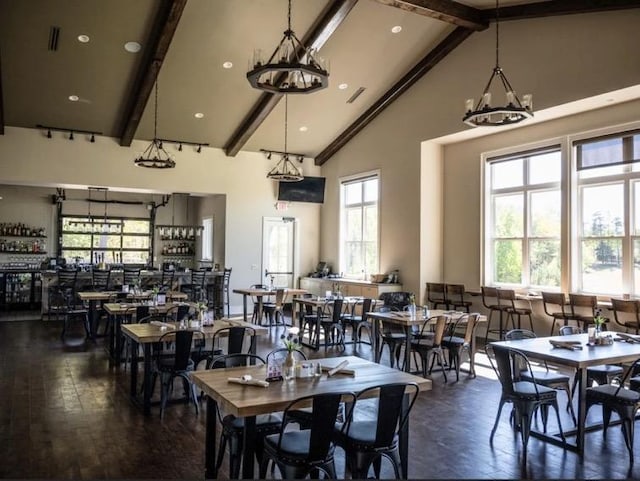 dining room featuring beamed ceiling, bar area, and high vaulted ceiling