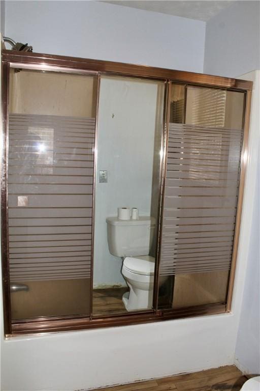 bathroom featuring toilet, shower / bath combination with glass door, and hardwood / wood-style floors