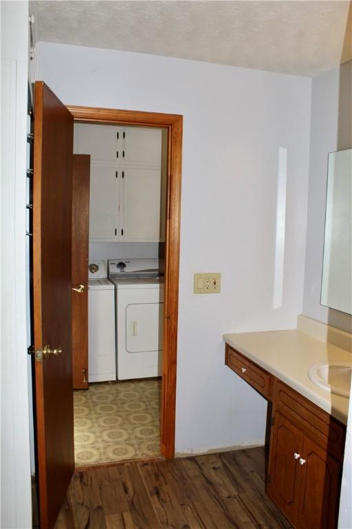 clothes washing area with cabinets, washing machine and dryer, sink, and dark wood-type flooring