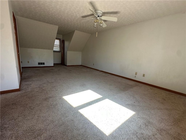 additional living space with ceiling fan, lofted ceiling, light colored carpet, and a textured ceiling