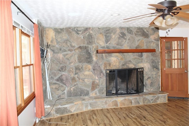 unfurnished living room with wood-type flooring, ceiling fan, and a fireplace