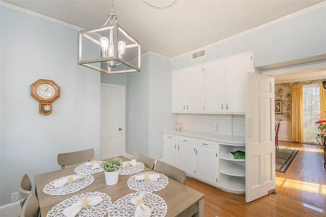 dining area with crown molding, light hardwood / wood-style flooring, and a chandelier