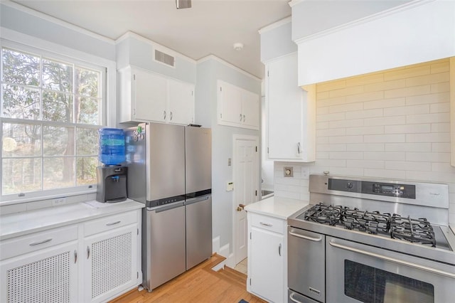 kitchen with stainless steel appliances, light wood-type flooring, white cabinets, and backsplash