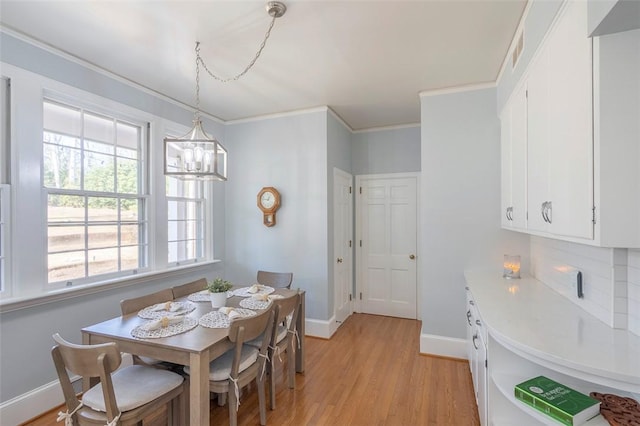 dining room with crown molding, an inviting chandelier, and light hardwood / wood-style floors