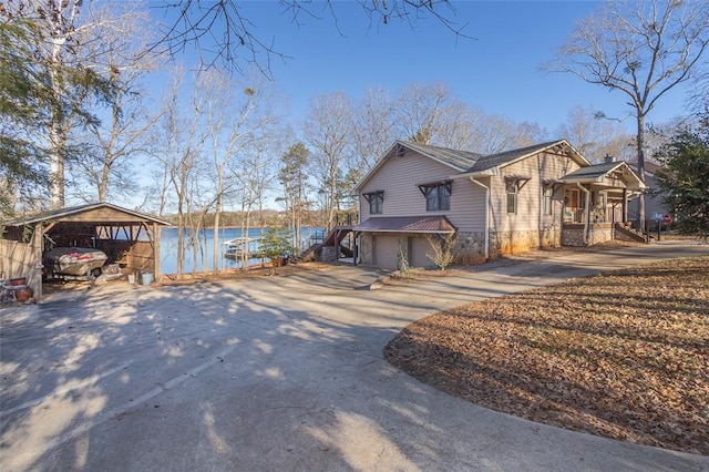 view of side of home featuring a carport, a porch, and a water view