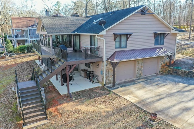 rear view of house featuring a garage, a sunroom, and a patio area