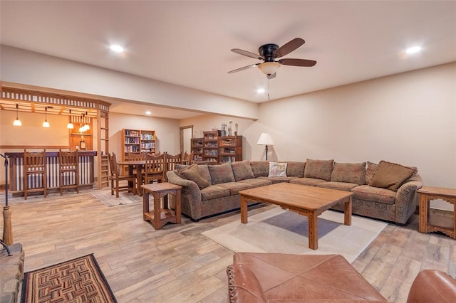 living room with wood-type flooring, bar, and ceiling fan