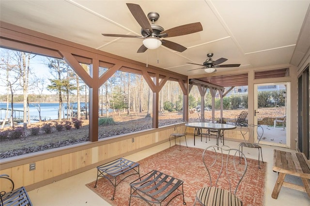 sunroom with ceiling fan and a water view