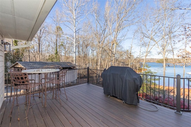 wooden deck featuring a water view and a grill