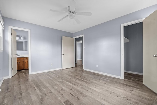 unfurnished bedroom with a spacious closet, connected bathroom, light wood-type flooring, and a closet