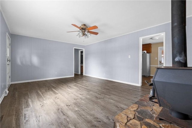 unfurnished living room featuring ornamental molding, a wood stove, dark wood-type flooring, and ceiling fan