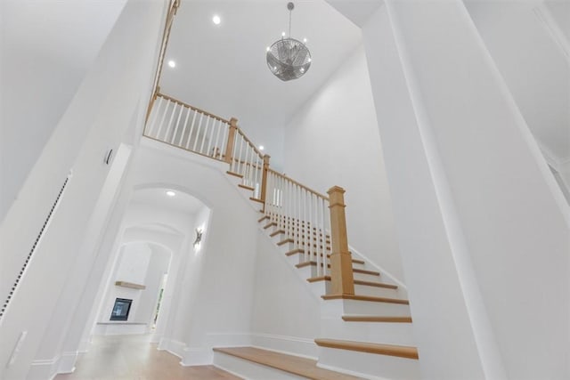 stairway with wood-type flooring, a towering ceiling, and a large fireplace