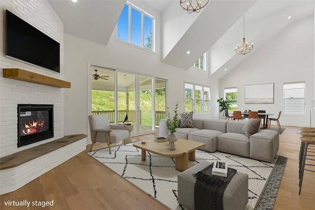 living room featuring lofted ceiling, a notable chandelier, light hardwood / wood-style floors, and a fireplace