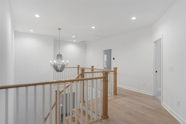 hallway with a notable chandelier and light wood-type flooring