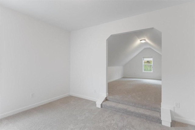 additional living space featuring lofted ceiling and light carpet