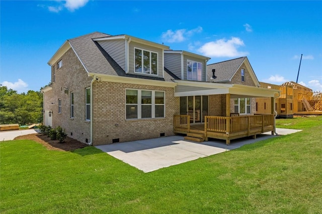 rear view of property with a deck, a patio area, and a lawn