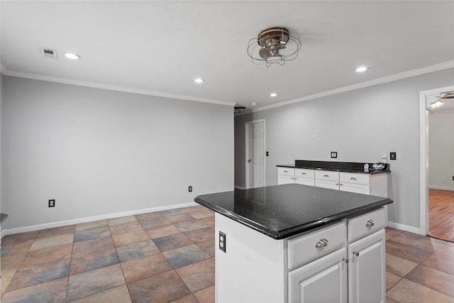 kitchen featuring ornamental molding, a kitchen island, and white cabinets