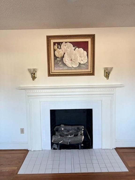 details featuring a tiled fireplace, hardwood / wood-style flooring, and a textured ceiling