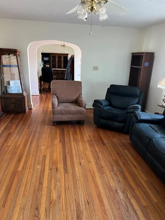 living room with ceiling fan, wood-type flooring, and a textured ceiling