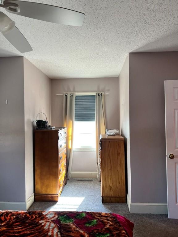 unfurnished bedroom with ceiling fan, carpet floors, and a textured ceiling