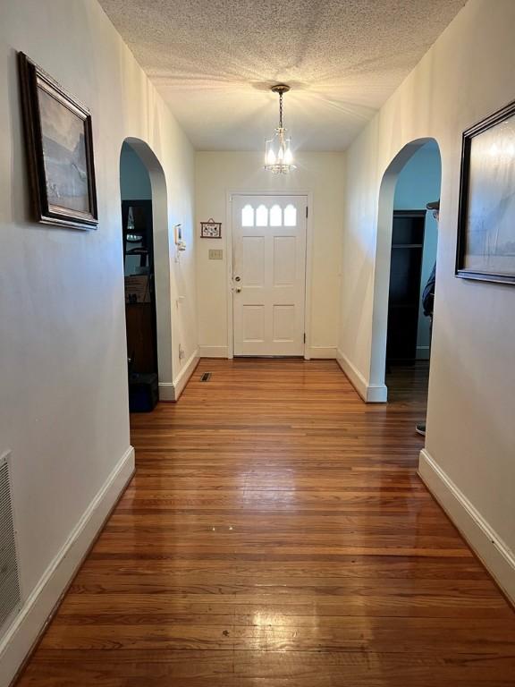 foyer entrance featuring wood-type flooring, an inviting chandelier, and a textured ceiling