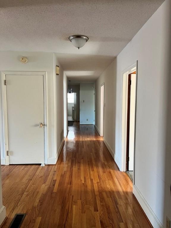 corridor featuring hardwood / wood-style flooring and a textured ceiling