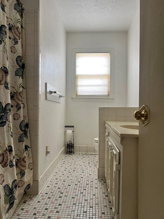 bathroom with tile patterned flooring, vanity, a textured ceiling, a shower with curtain, and toilet