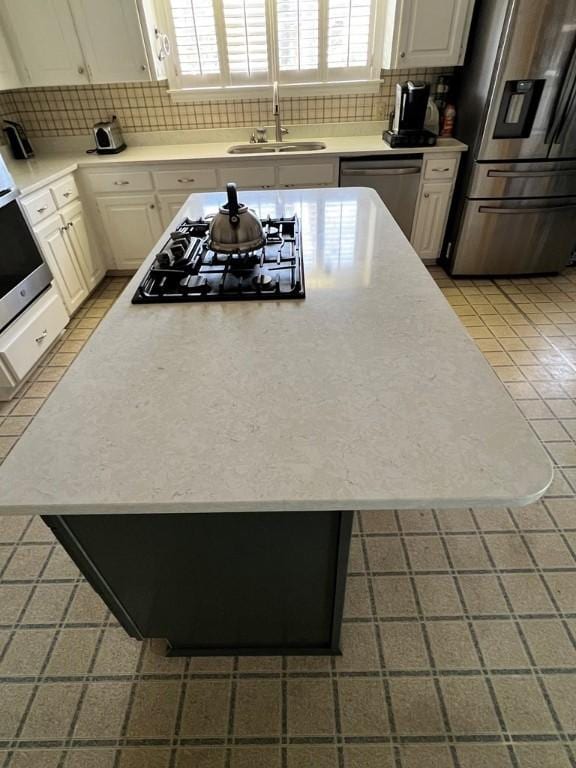 kitchen featuring tasteful backsplash, sink, white cabinets, and appliances with stainless steel finishes