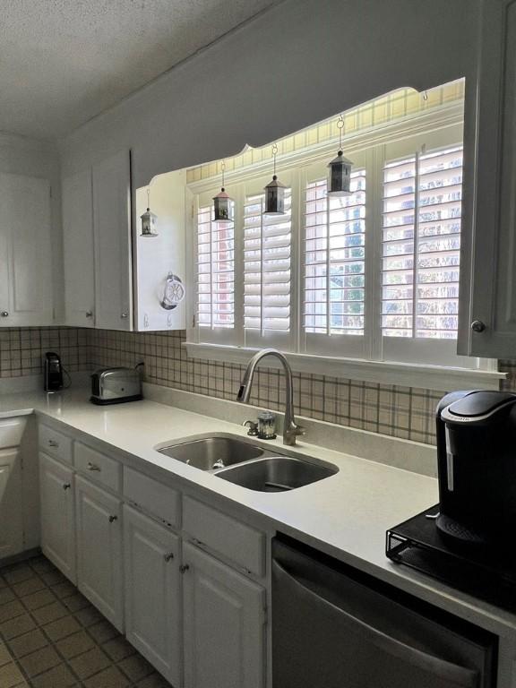 kitchen with sink, white cabinetry, decorative light fixtures, dishwasher, and decorative backsplash