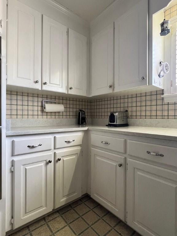 kitchen with tasteful backsplash and white cabinetry