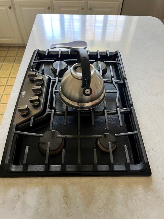 interior details featuring black gas stovetop and white cabinets